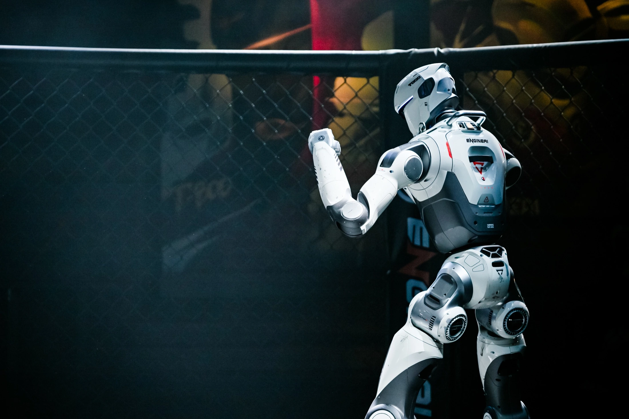 White humanoid robot moving inside a competition enclosure